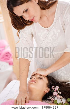 Careful messeur doing facial massage on pretty lady at bright room of modern spa salon