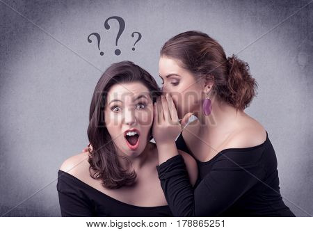 A teenager girl looking confused with drawn question marks above the head, while a girlfriend whispers something in her ear concept.