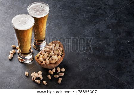 Lager beer glasses and pistachio nuts on stone table. View with copy space