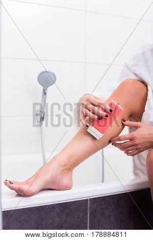 Woman in bathroom applying epilation lotion on legs