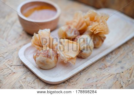 Deep fried shrimp dumplings with sauce on wooden table in Thailand