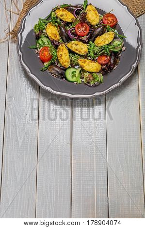 Delicious Seafood salad with vegetables and mussels on wooden table in rustic style. The original presentation of the dish from the chef. Copy space