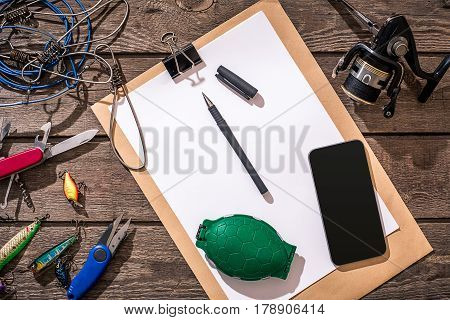 Fishing tackle - fishing spinning, fishing line, hooks and lures on wooden background. Top view. Copy space. Still life