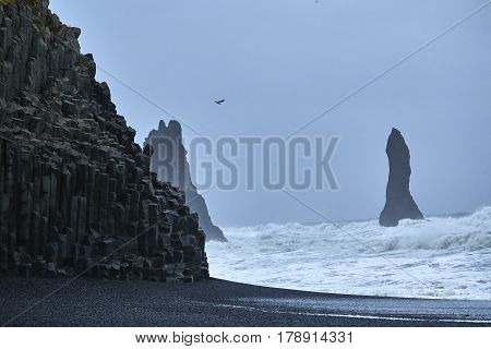 Reynishverfisvegur, Reynisfjara black sand beach with rocks, ocean and dark rain and storm clouds near the village of Vik in Iceland.