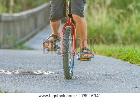 outdoor portrait of young boy riding a unicycle (one wheel bike) on natural background