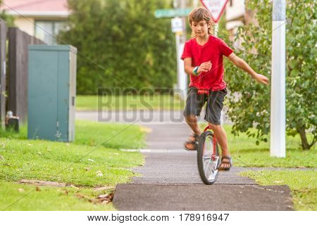 outdoor portrait of young boy riding a unicycle (one wheel bike) on natural background