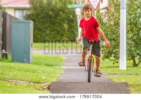 outdoor portrait of young boy riding a unicycle (one wheel bike) on natural background