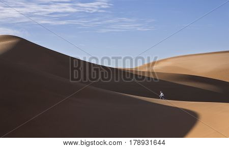 young man walking in sand dunes in Liwa desert in Abu Dhabi