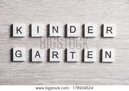 Alphabet letters on wooden pieces collected to word kinder garten