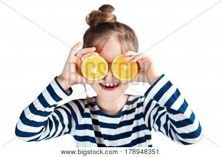 A girl with oranges on a background in the studio closes her eyes and laughs