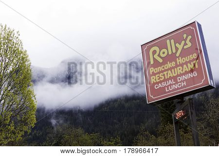 Hope, British Columbia - April 24, 2015 -- Wide view looking at the bright red sign at Rolly's Restaurant in Hope, British Columbia on a bright overcast day in April.