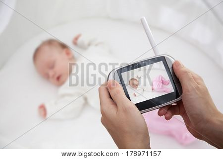 Mother Hand holding video baby monitor for security of the baby