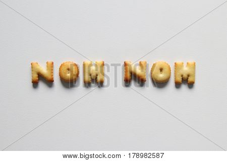 An Inscription From The Cookies On The White Background. Text – Nom Nom.