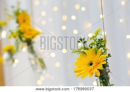 The marigold flowers in a glass bottle hanging. Flower vase arrangements on blurred background and bokeh
