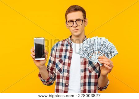 A Man Wearing Glasses And A Plaid Shirt Shows His Cash Prize And A Blank Screen Of A Smartphone, On