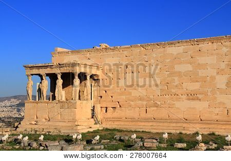Caryatid Statues On The Porch Of The Erechtheion On The Acropolis In Athens, Greece With Blue Sky An