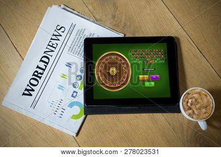 Online Roulette Game  against digital tablet with coffee and newspaper on table