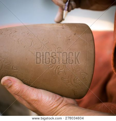 Ceramic Workshop, The Master Puts Otnament On Unfired Earthenware Jug. Close-up Of Master Hands. Mad