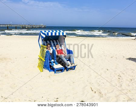 Teens Enjoy Sunbath In The Roofed Wicker Beach Chair