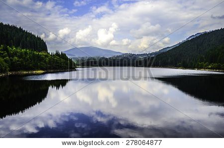 Beautiful Oasa Lake Between The Mountains Mirroring The Clouds And The Sky, Transalpina Road, Romani