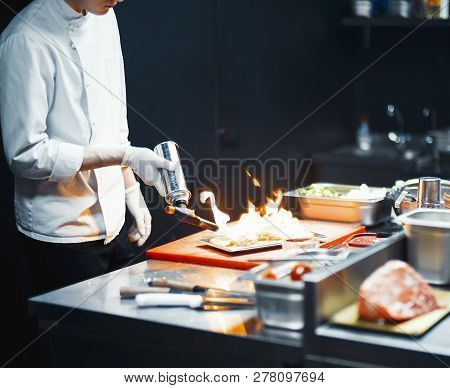 Restaurant Chef Cook Preparing Salmon Filet Flambe In Open Kitchen.