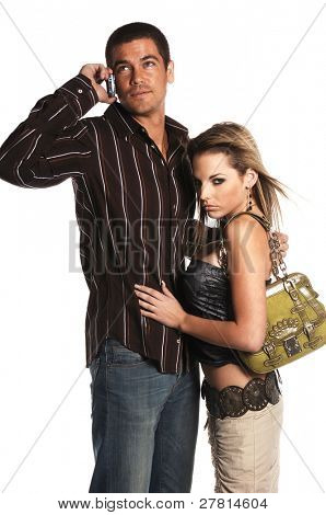 Glamorous couple fashionably dressed with the man talking on a cell phone and ignoring the woman