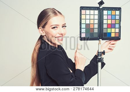 Young Photographer Pointing At Color Checker Card, While Working In Studio. Girl In Formal Suit Prep