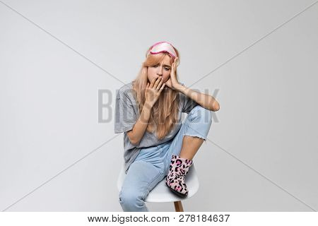 Studio Portrait Of Young Bored Woman In Grey T-shirt Covering Mouth With Hand, Front View/drowsiness