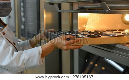 Woman Cooking In The Kitchen, Puts Cakes In The Oven