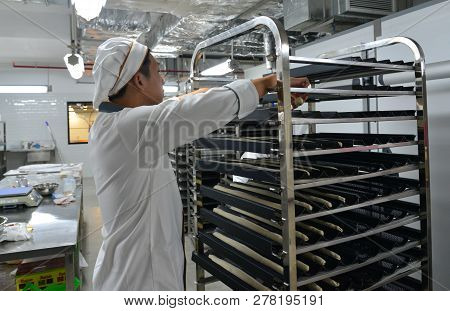 Saigon, Vietnam - Jan 9, 2018. A Man Working With Racks Of Freshly Baked Bread At The Factory In Sai