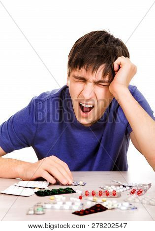 Young Man With A Pills Yawning On The Table Isolated On The White Background