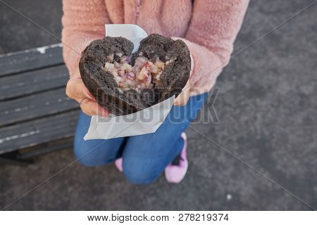 People Hold The Squid Bun With Color Of Squid Ink On Hand