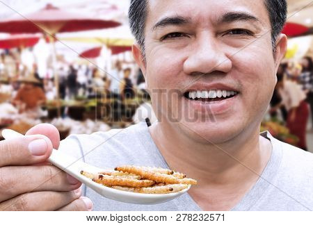 Man Opening His Mouth Eating Bamboo Worm Insect Or Bamboo Caterpillar On Spoon At Market. Food Insec