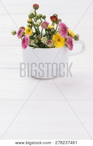Immature Flowers In White Mug. White Wooden Table Background.