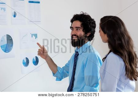 Arabic Businessman And Turkish Businesswoman Talking About Strategy At Office Of Company