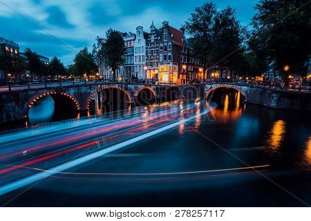 Famous Amsterdam Canal And Magic Light Trails Of A Vessel