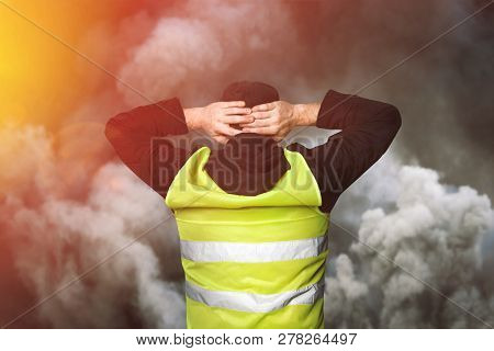 Yellow Vests Protests. Young Man Stands With His Back And Holds His Hands On His Head As A Sign Of O