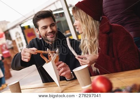 Close-up Of Young Couple Are Eating Churros At The Street Food Market.