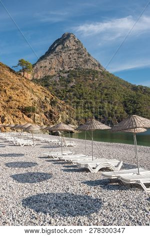 Beach umbrellas and sunbeds on the Adrasan beach at Mediterranean coast in Turkey