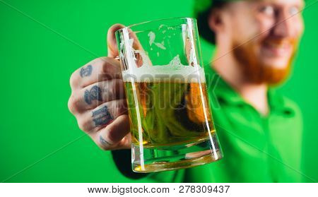 Portrait Of Excited Man Holding Glass Of Beer On St Patricks Day Isolated On Green