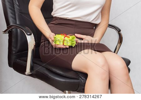 The Girl Sits In The Office In A Computer Chair And Holds On To The Lower Abdomen, In Her Other Hand