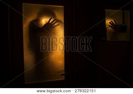 Horror Silhouette Of Woman In Window. Scary Halloween Concept Blurred Silhouette Of Witch In Bathroo