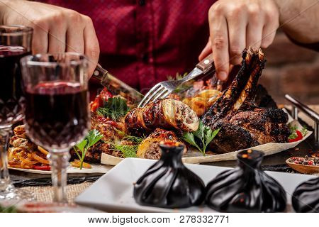 Traditional Georgian And Armenian Cuisine. A Man Holds A Knife And A Fork In His Hands, And There Is