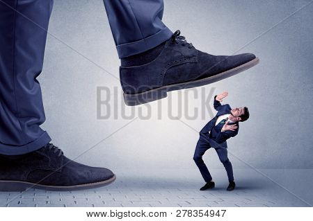 Young handsome businessman getting crushed by a big formal shoe