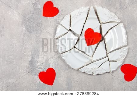 Broken Heart Concept. Divorse, Quarrel. Broken Vintage Porcelain Plate On Old Grey Background. Smith