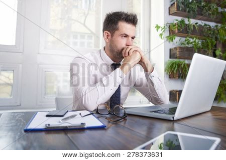 Careworn Businessman Sitting In Front Of Laptop And Working
