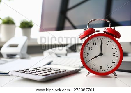 Red Alarm Clock Set At Eight In The Morning Closeup Standing On Office Table. Business Or Education 