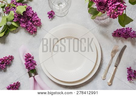 Spring Table Place Setting With Lilac Flowers, Silverware On Light Table. Top View.