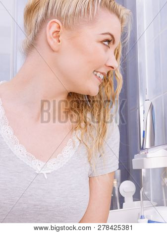 Woman In Bathroom Looking At Mirror