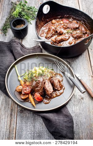 Traditional German braised pork cheeks in brown sauce with mushroom and mashed potatoes as closeup on a modern design plate 